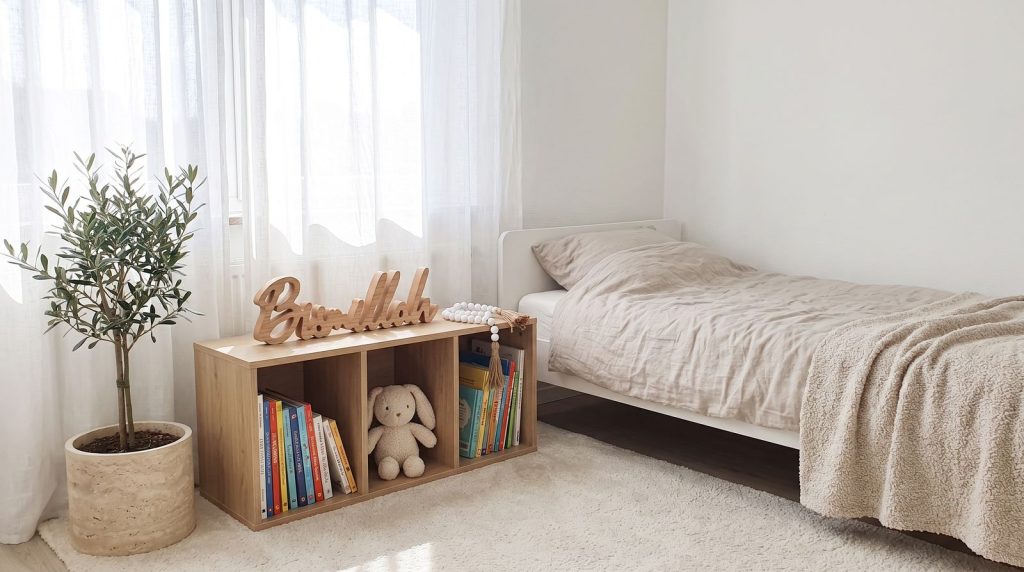 Kinderzimmer mit dem Wort Bismillah aus Holz und einer Perlenkränze aus weißem Glas