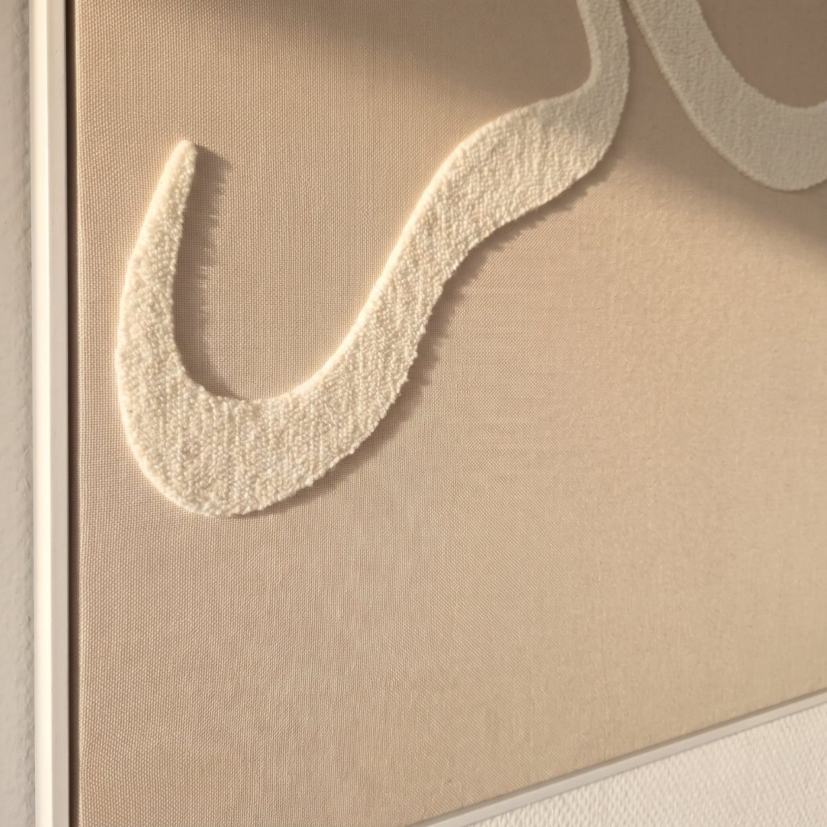 Détail de la calligraphie tuftée beige en relief sur tissu taupe